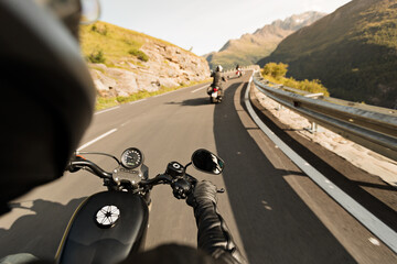 Motorcycle driver riding in Alpine highway, handlebars view, Dolomites, central Europe.