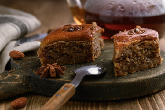 Baklava - an image on a natural wooden background of an Oriental dessert made of puff pastry with honey and nuts.