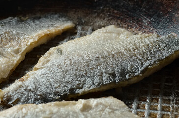 Sea bass fillet fried in a pan, seafood.