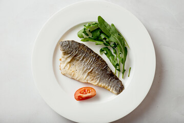 Sea bass fillet fried on a plate, seafood.
