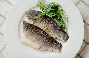 Sea bass fillet fried on a plate, seafood.