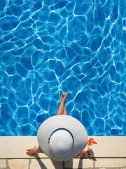Fototapeta na wymiar beautiful woman with cocktail sitting on the edge of the swimming pool, relaxation concept