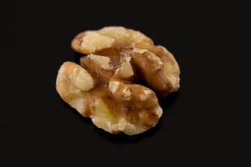macro shot of a single walnut half on a black background with slight reflection