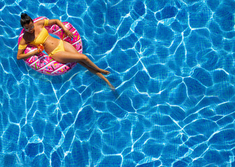 beautiful woman sitting in inflatable donut at swimming pool, relaxation concept
