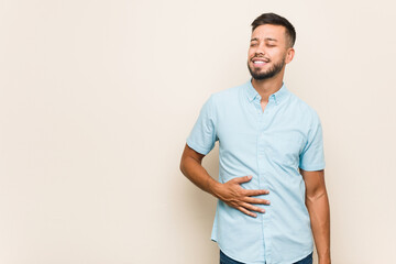 Fototapeta premium Young south-asian man touches tummy, smiles gently, eating and satisfaction concept.