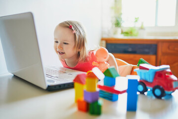 Happy toddler girl with laptop and toys