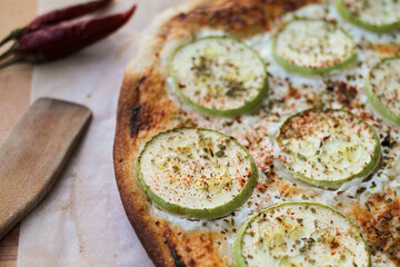 Pizza with zucchini and cheese sprinkled with hot ground pepper and dried oregano. Vegetarian pizza.