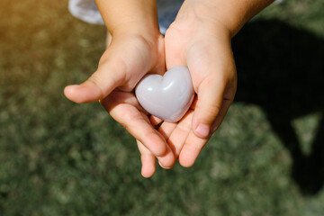 Close up of child hands holding a silver heart.