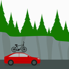 Red passenger car with a bicycle on the roof on a background of mountains and forest