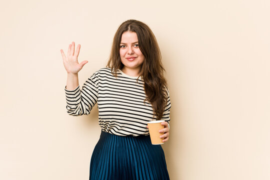 Young curvy woman holding a coffee smiling cheerful showing number five with fingers.