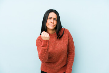 Young caucasian woman isolated on a blue background showing fist to camera, aggressive facial expression.