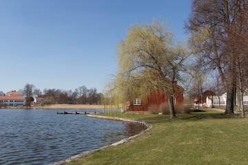 Fototapeta na wymiar Mariefred, Sweden - April 20 2019: the view of embankment of lake Malaren with typical swedish red building in a sunny day on April 20 2019 in Mariefred, Sweden.