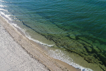 azure water and white foam from the waves on the coast of the island. top view