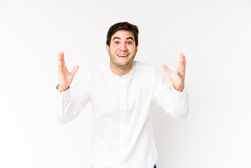 Fototapeta premium Young man isolated on white background receiving a pleasant surprise, excited and raising hands.