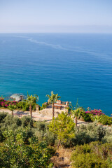 Naklejka premium A view of the Mediterranean coast with waves of azure water. Summer seascape. Seaside in sunny weather. Beautiful sea view
