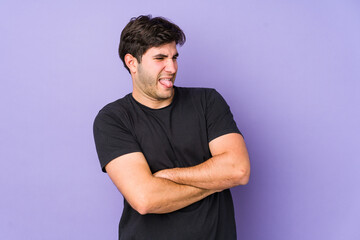 Fototapeta premium Young man isolated on purple background funny and friendly sticking out tongue.