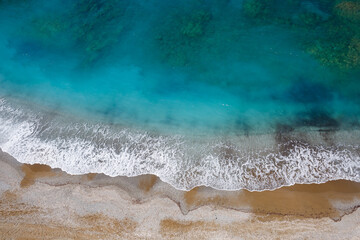 Top view of the sea coast with azure water and sandy beach. Aerial photo of the Mediterranean Sea with coastline. Beautiful sea in the summer season, filmed from a drone