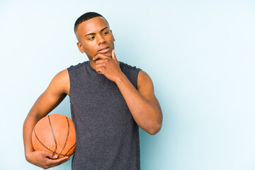 Obraz premium Young colombian man playing basketball isolated relaxed thinking about something looking at a copy space.