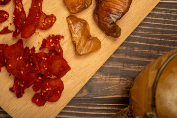 Dried halibut caviar and dried crab meat on a wooden serving Board and a mug of beer on a wooden table. Close up.