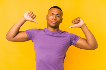 Young latin man isolated on yellow background feels proud and self confident, example to follow.