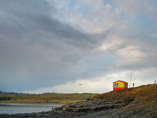 Vivid red and yellow lifeguard house overlooking ocean. Nobody. Rosses point beach county Sligo, Ireland. Dramatic cloudy sky.