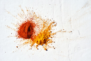 Close-up plan splash of various powder spices of chili and turmeric on a white background.