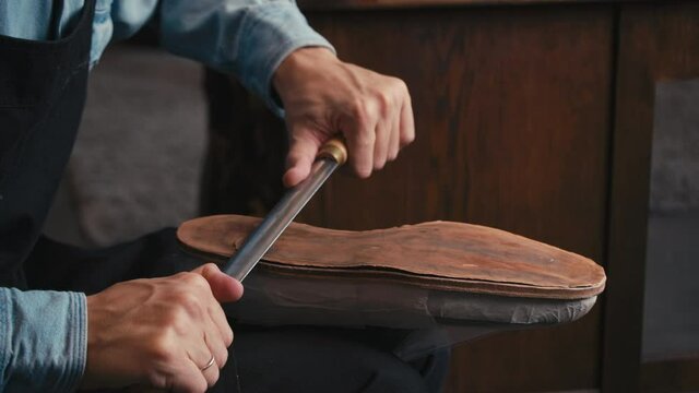 Close up shoemaker polishing sole shoe. Shoemaker sews shoes. Craft production. Cinematic light