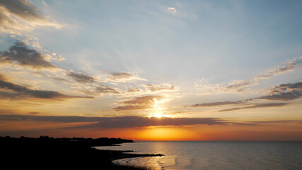 Fototapeta na wymiar Calm sea with sunrise sky and sun through the clouds over. Golden sunrise with blue waves. 