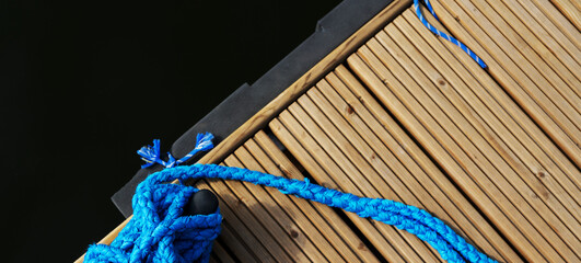 Yacht rope detail image on figure eight cleat hitch on wooden deck. Close up of boat rope tied with...