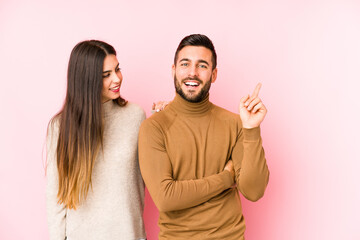 Young caucasian couple isolated smiling cheerfully pointing with forefinger away.