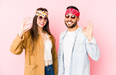 Young caucasian couple wearing a music festival clothes isolated cheerful and confident showing ok gesture.