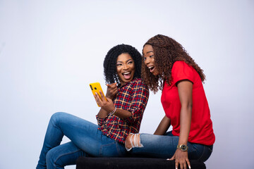 beautiful young african lady showing her friend something exciting on her phone