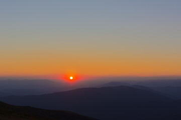 The first or last rays of the sun on a mountain pass. Morning and evening in nature. Colorful sunset and sunrise over the mountain hills. Carpathians in summer and autumn.