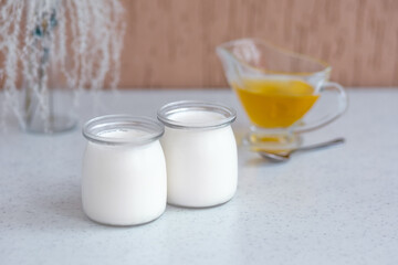 two glass jars with classic thermostat yoghurt and honey.