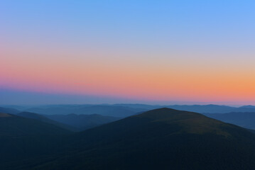 The first or last rays of the sun on a mountain pass. Morning and evening in nature. Colorful sunset and sunrise over the mountain hills. Carpathians in summer and autumn.
