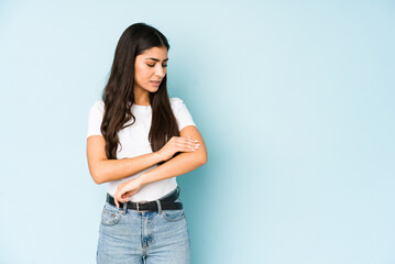 Young indian woman on blue background massaging elbow, suffering after a bad movement.