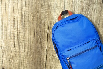Blue school bag with school supplies on desk