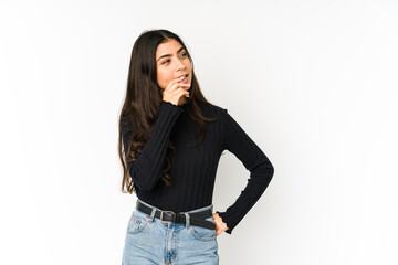 Young indian woman isolated on purple background relaxed thinking about something looking at a copy space.