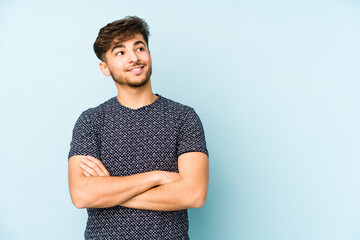 Young arabian man isolated on a blue background smiling confident with crossed arms.