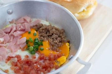 Pan-fried eggs with toppings on a wooden cutting board and nutritious breakfast bread.