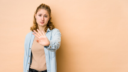 Obraz premium Young caucasian woman isolated on beige background rejecting someone showing a gesture of disgust.