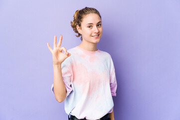 Young caucasian woman on purple background cheerful and confident showing ok gesture.