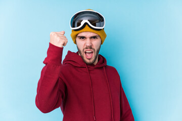 Young caucasian man wearing a ski clothes isolated showing fist to camera, aggressive facial expression.