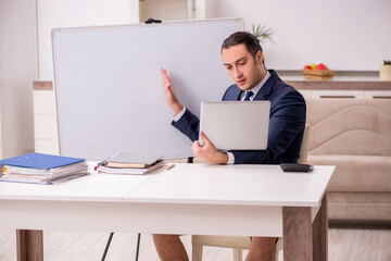 Young male employee working at home during pandemic disease