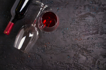 Bottle of red wine, wine glass on black background, copy space. View from above, top studio shot
