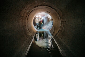 Sewer tunnel workers examines sewer system damage and wastewater leakage - obrazy, fototapety, plakaty