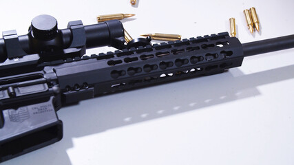 Tactical rifle with a colimator sight and some ammunition on the table. 