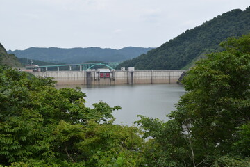 Fototapeta na wymiar 月山ダム（がっさんダム）／ 山形県鶴岡市の一級河川、赤川水系の梵字川に建設されたダムです。高さ123メートルの重力式コンクリートダムで、洪水調節、不特定利水、上水道、発電を目的とする、国土交通省直轄の多目的ダムです。ダム湖（人造湖）は、あさひ月山湖（あさひがっさんこ）と言います。