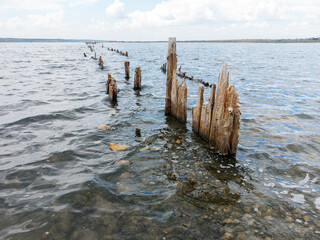 Salty estuary Kuyalnik, dead lake near Odessa, Ukraine. Wooden sticks reflected in blue water at sunny weather.