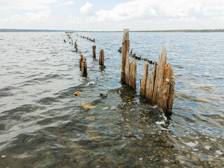 Salty estuary Kuyalnik, dead lake near Odessa, Ukraine. Wooden sticks reflected in blue water at sunny weather.